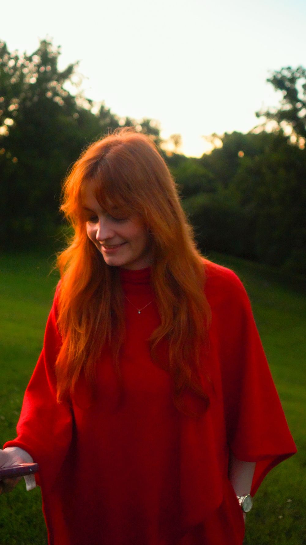 Shannon smiling in a red poncho at golden hour