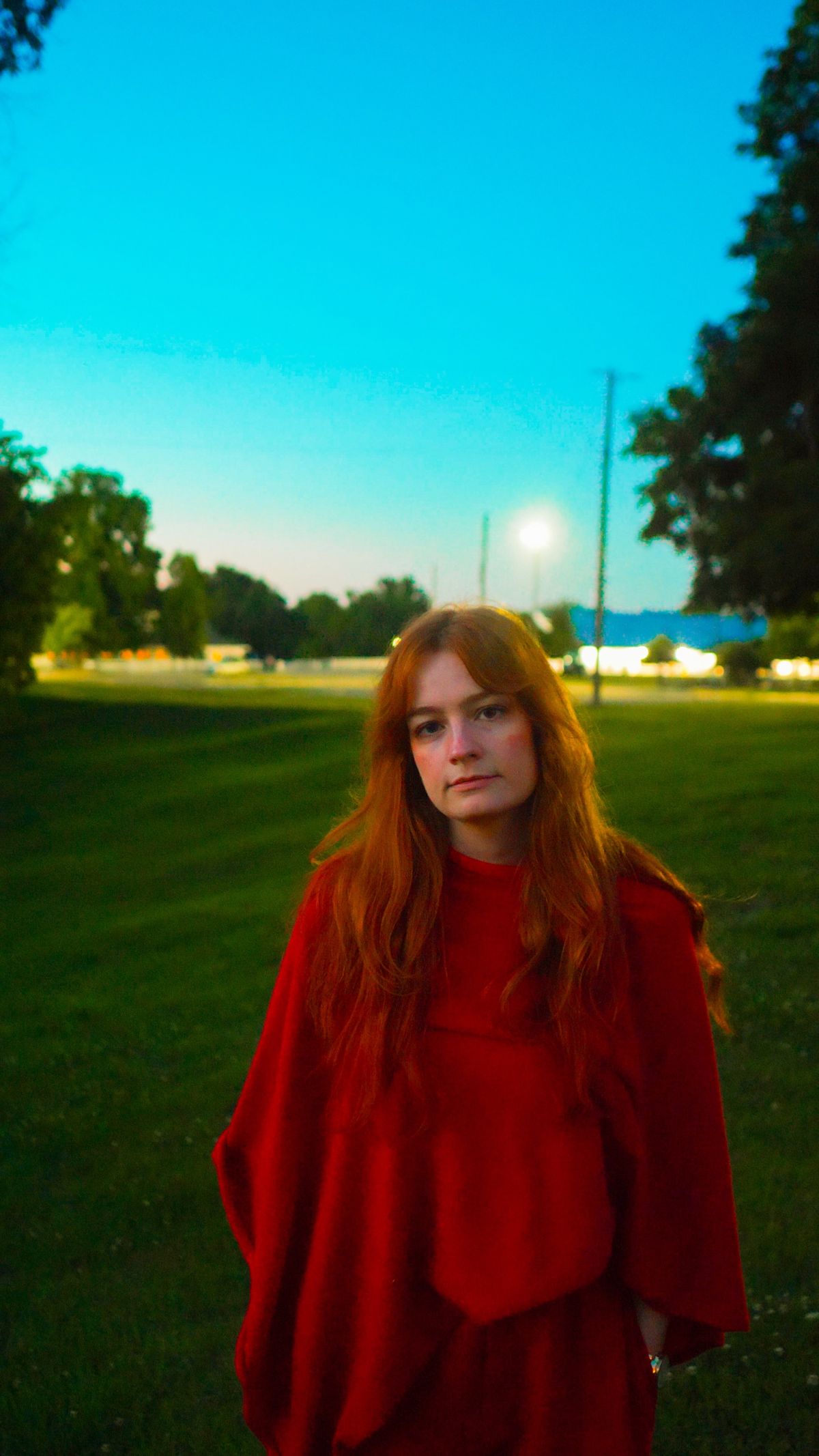 Shannon McNeal in red in a field under an evening sky